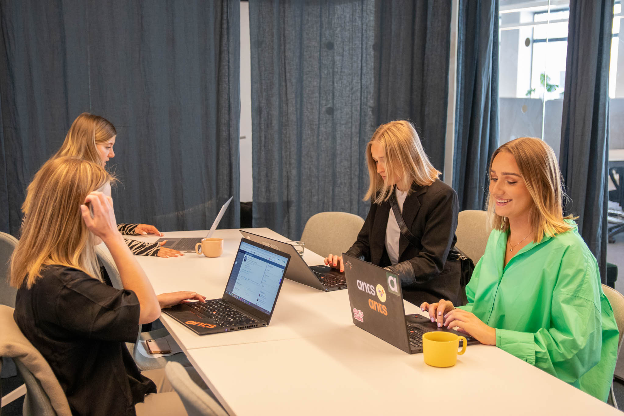 Fyra personer sitter vid ett bord framför laptops och läser om att rekrytera en Head of User Experience.