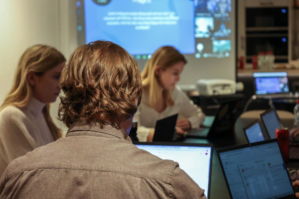 Personer sitter vid ett bord framför laptops och läser om rollen Digital Analytics Manager.
