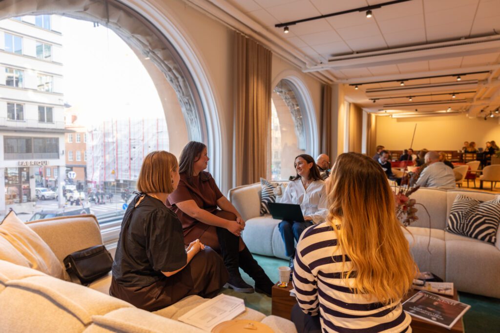 En grupp personer sitter i en soffgrupp och samtalar om custom-GPTs