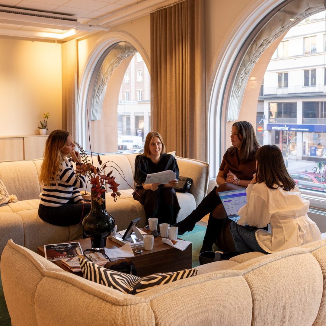 Fyra personer samtalar och arbetar med hållbara kompetenser. De sitter i en soffgrupp.