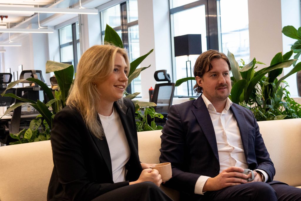 Anställda på företaget Ants som arbetar med IT-rekrytering sitter i en soffa och pratar med någon annan utanför bild. 