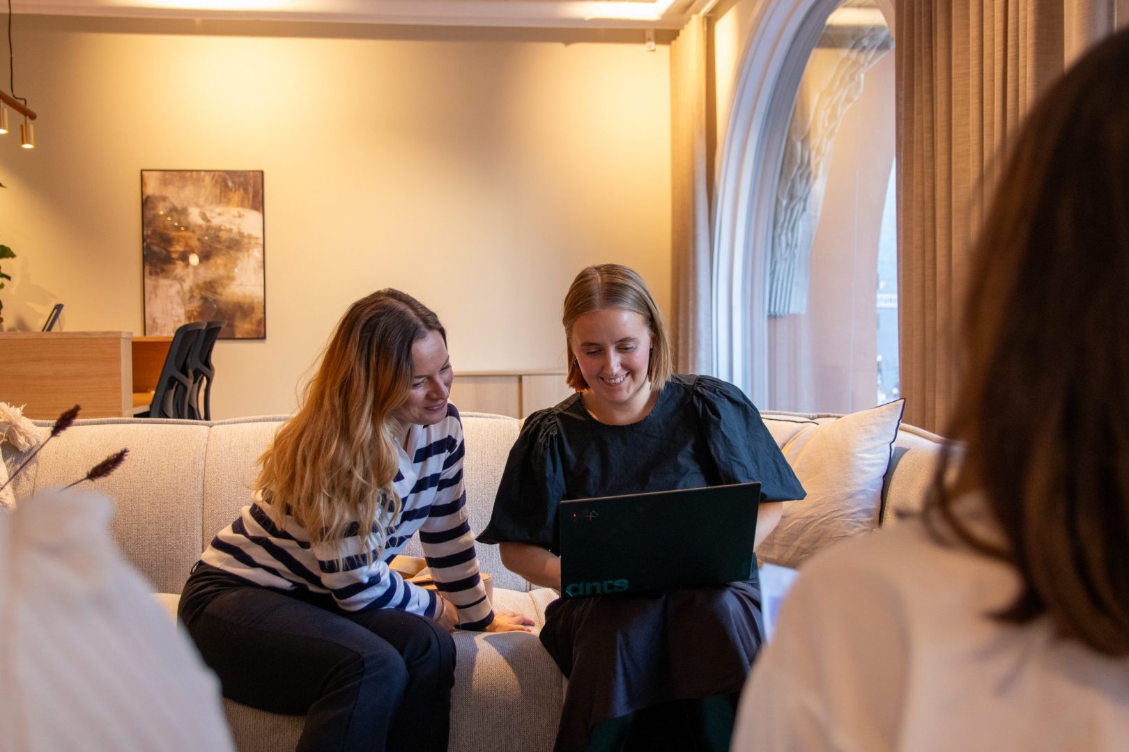 Två rekryterare sitter tillsammans i en soffa med en laptop och jobbar med IT-rekrytering.