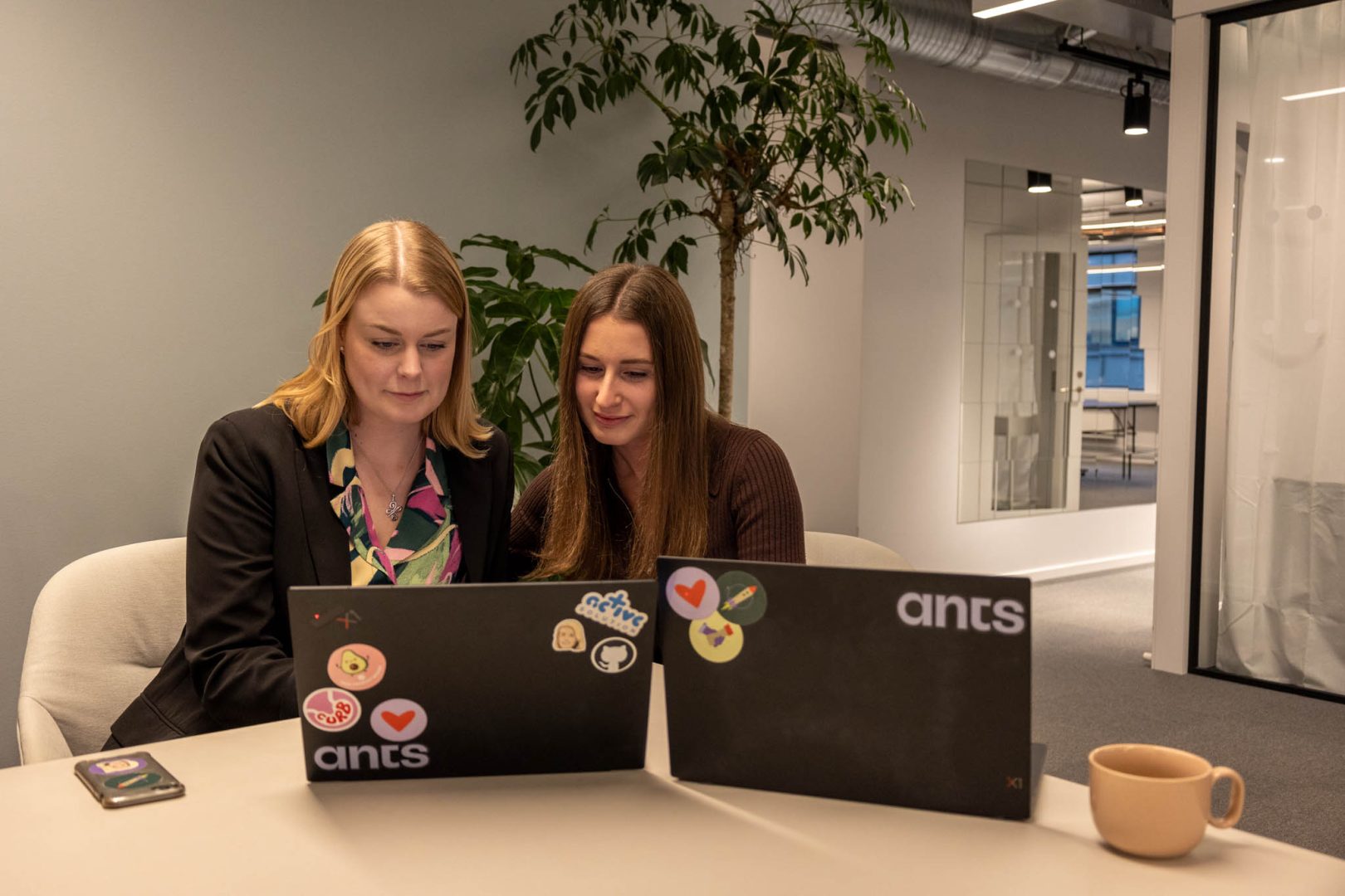 Två kvinnor arbetar framför datorer och analyserar e-handelsdata och digital marknadsföringsstrategier – viktiga kompetenser för en E-commerce Specialist.