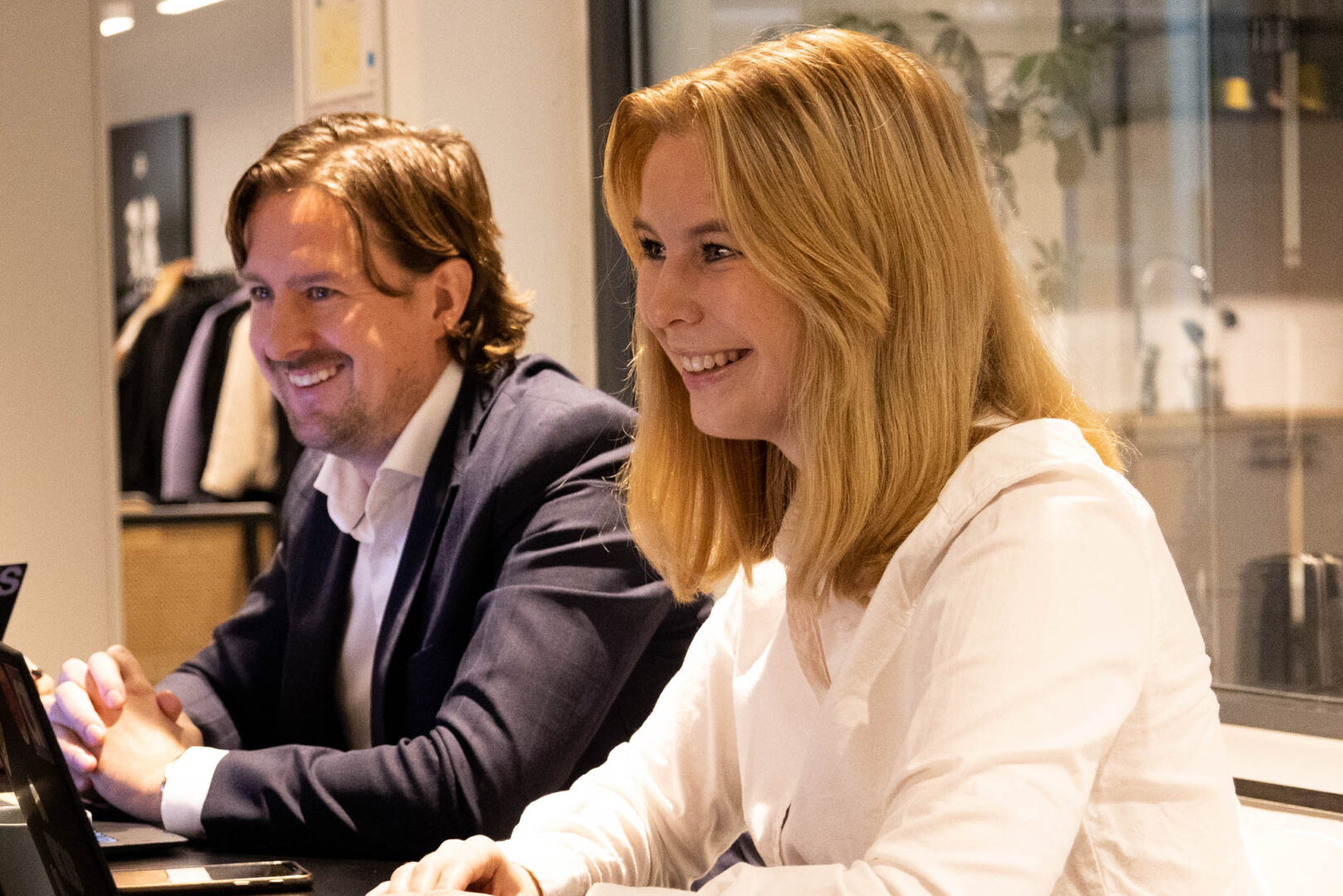 Två tekniska chefer sitter i ett mötesrum med en OEM-leverantör och ler.