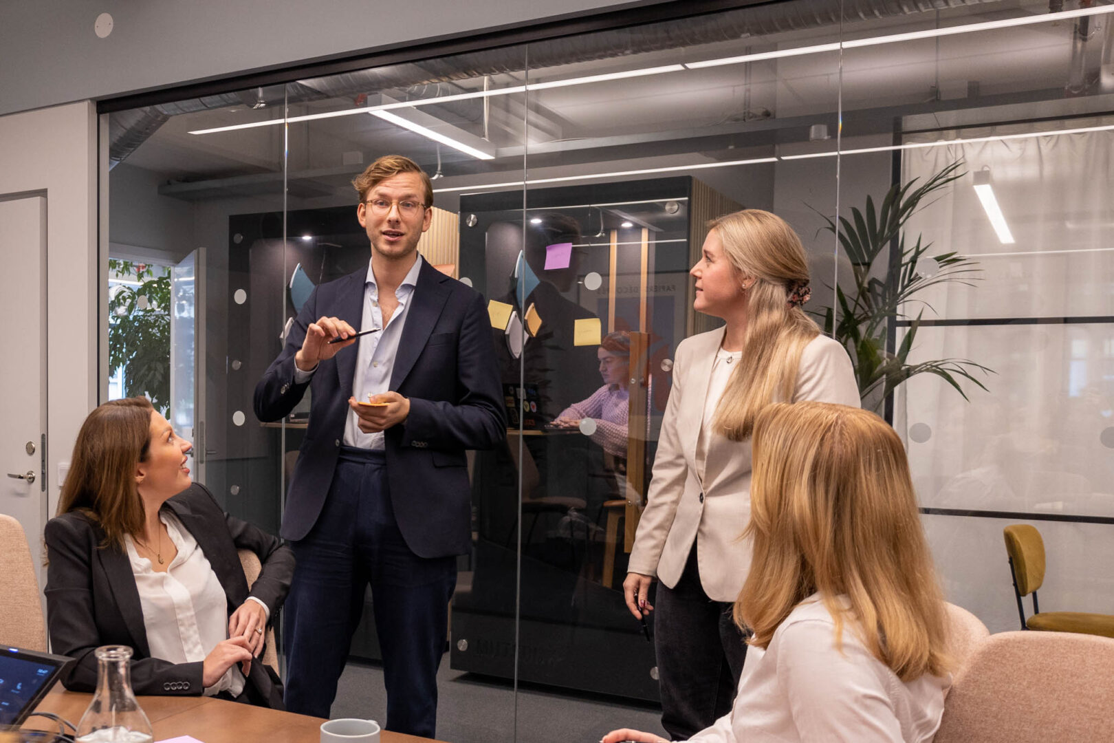 Chefer och ledare inom IT och marknadsföring på ett modeföretag har ett möte i ett inglasat rum och planerar nya MarTech-verktyg och byte av CRM-system.
