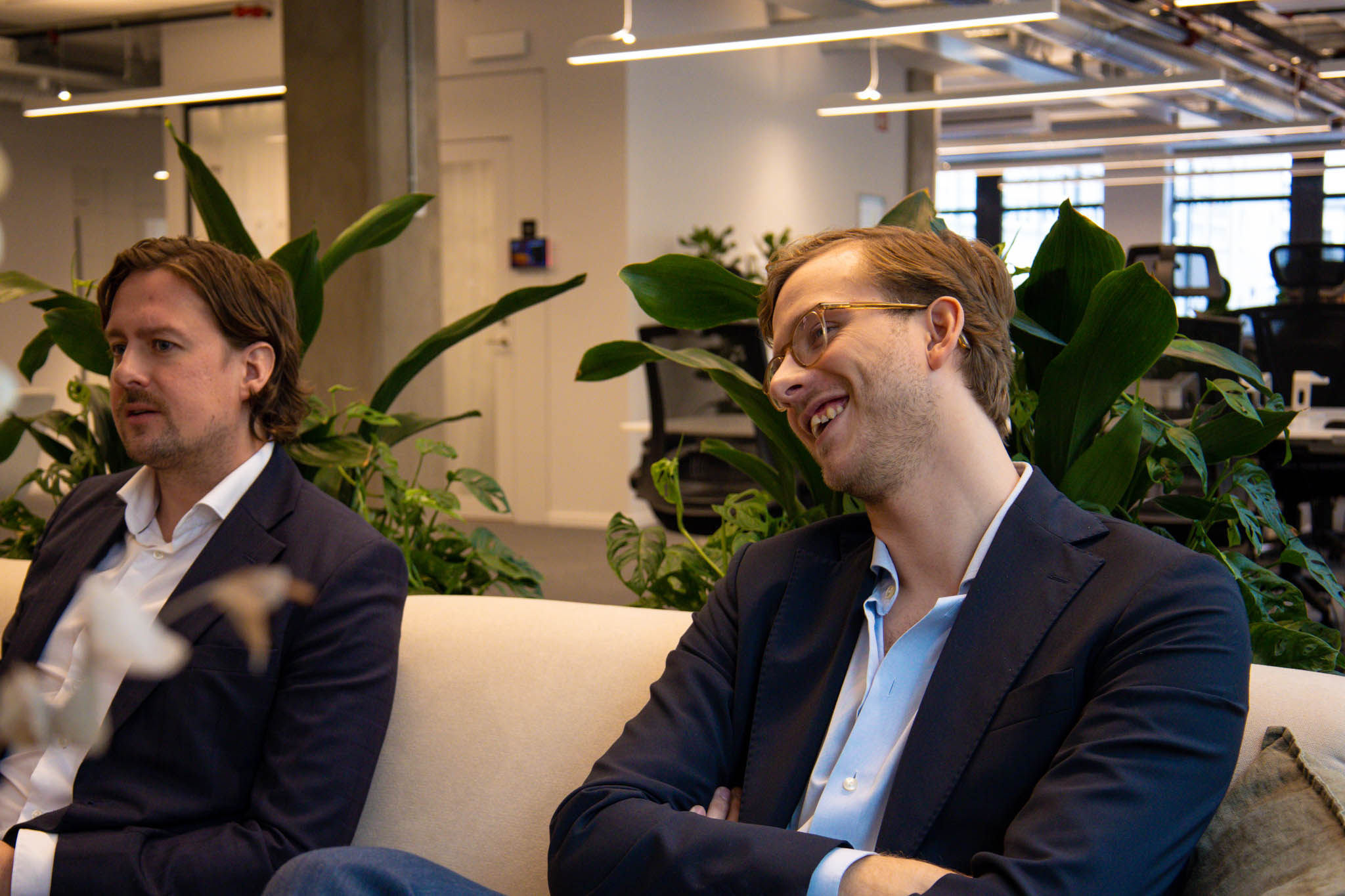 En glad hållbarhetschef på ett CleanTech-bolag sitter i en soffa och diskuterar grön teknik och teknologisk utveckling.