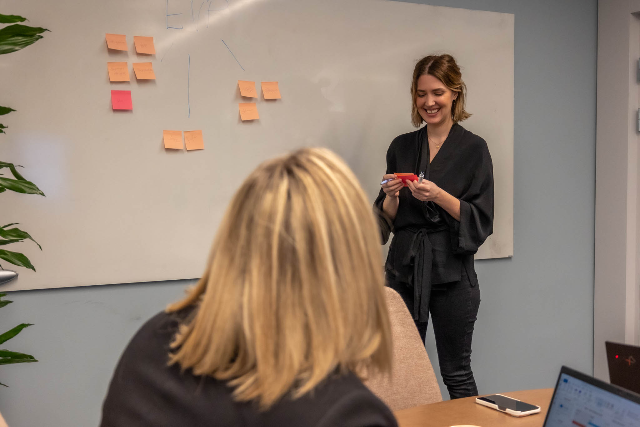 En CRM Campaign Manager på ett företag som skapar elbildsladdare står framför en whiteboard med färgglada post-it-lappar och mappar ut hur deras email marketing automation kan optimeras.