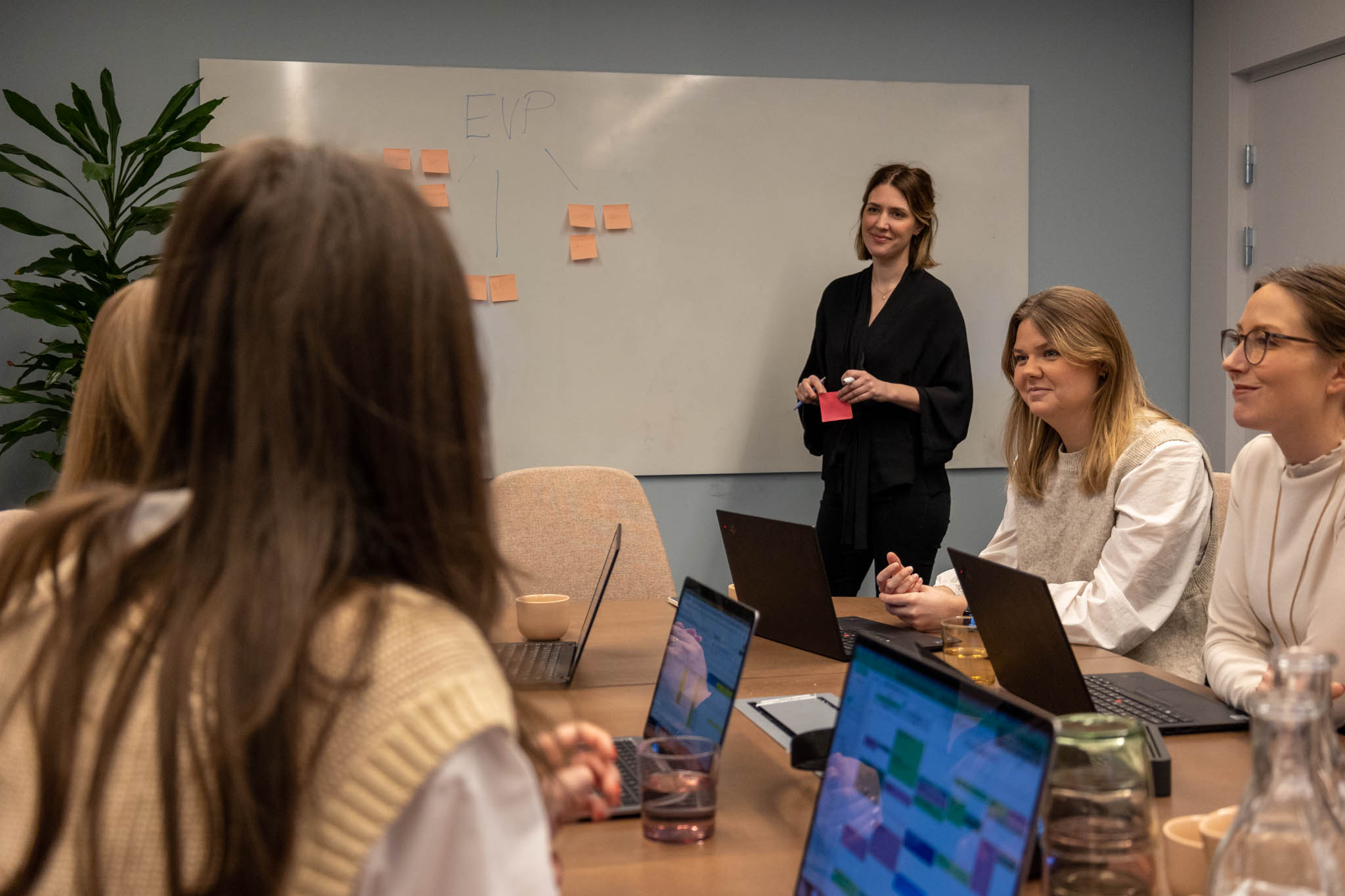 Ett tillväxtteam bl.a bestående av en Growth Hacker, Product Manager och Data Analyst sitter framför ett bord och en whiteboard med post-it-lappar, där de brainstormar och planerar datadrivna strategier för att driva snabb tillväxt och innovation i ett SaaS-företag.