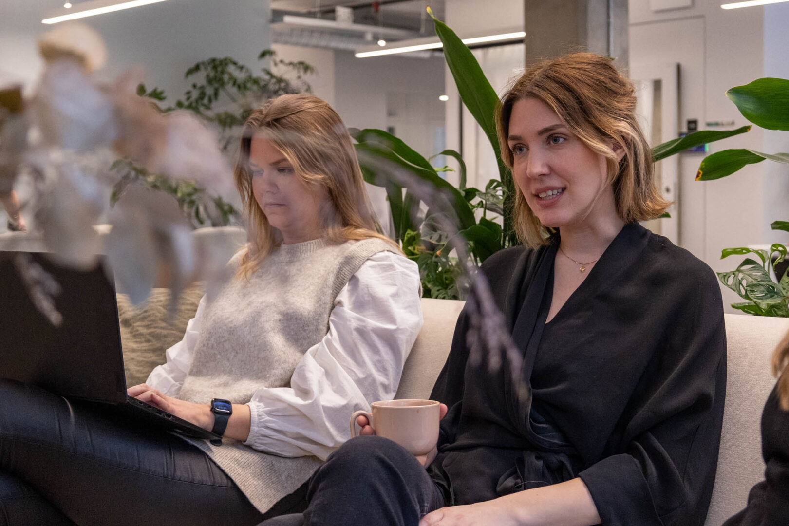 En UX Designer som arbetar på ett e-handelsbolag sitter i en soffa med en kopp kaffe i handen och berättar om resultaten från deras senaste användarundersökning.