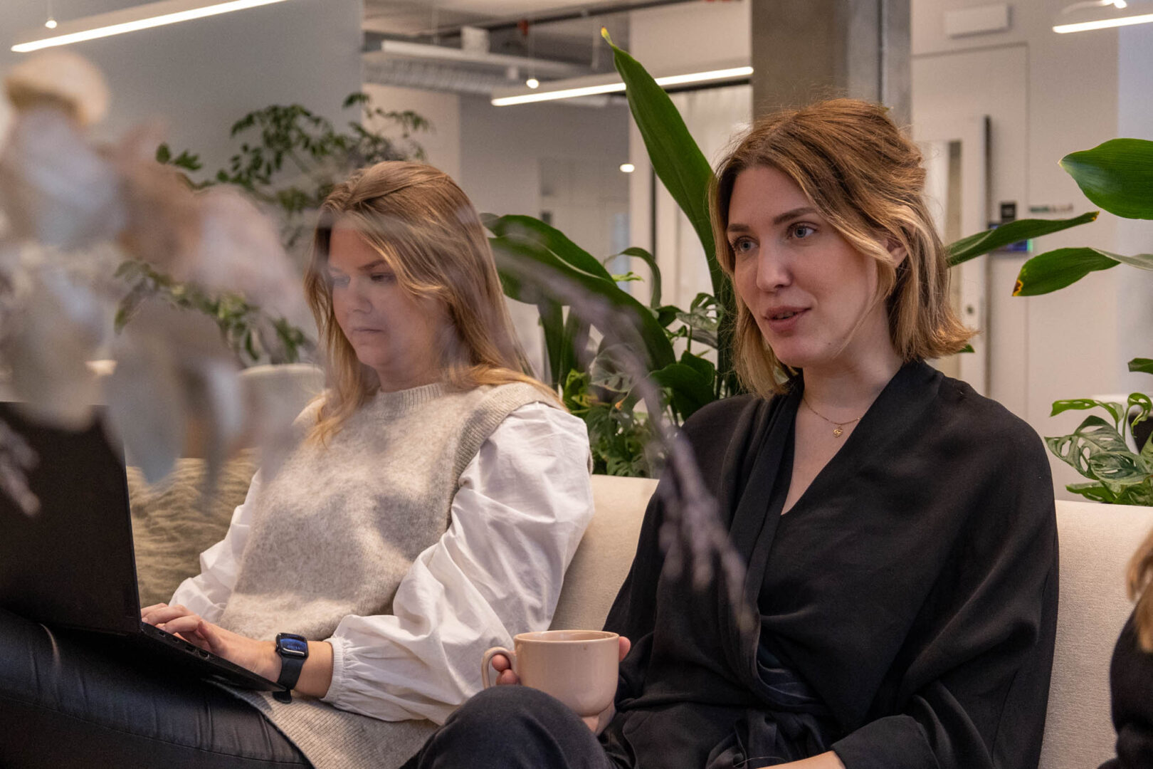 En marknadsförare på ett FinTech-företag sitter i en soffa med en kaffe i handen och diskuterar lanseringsstrategi för deras nya B2B-produkt.
