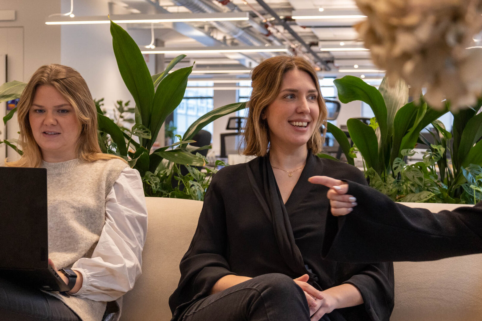 En kvinnlig IT-specialist inom Life Science ler medan hon diskuterar lösningar för dataskydd och regulatorisk efterlevnad med en kollega i en avslappnad mötesmiljö.