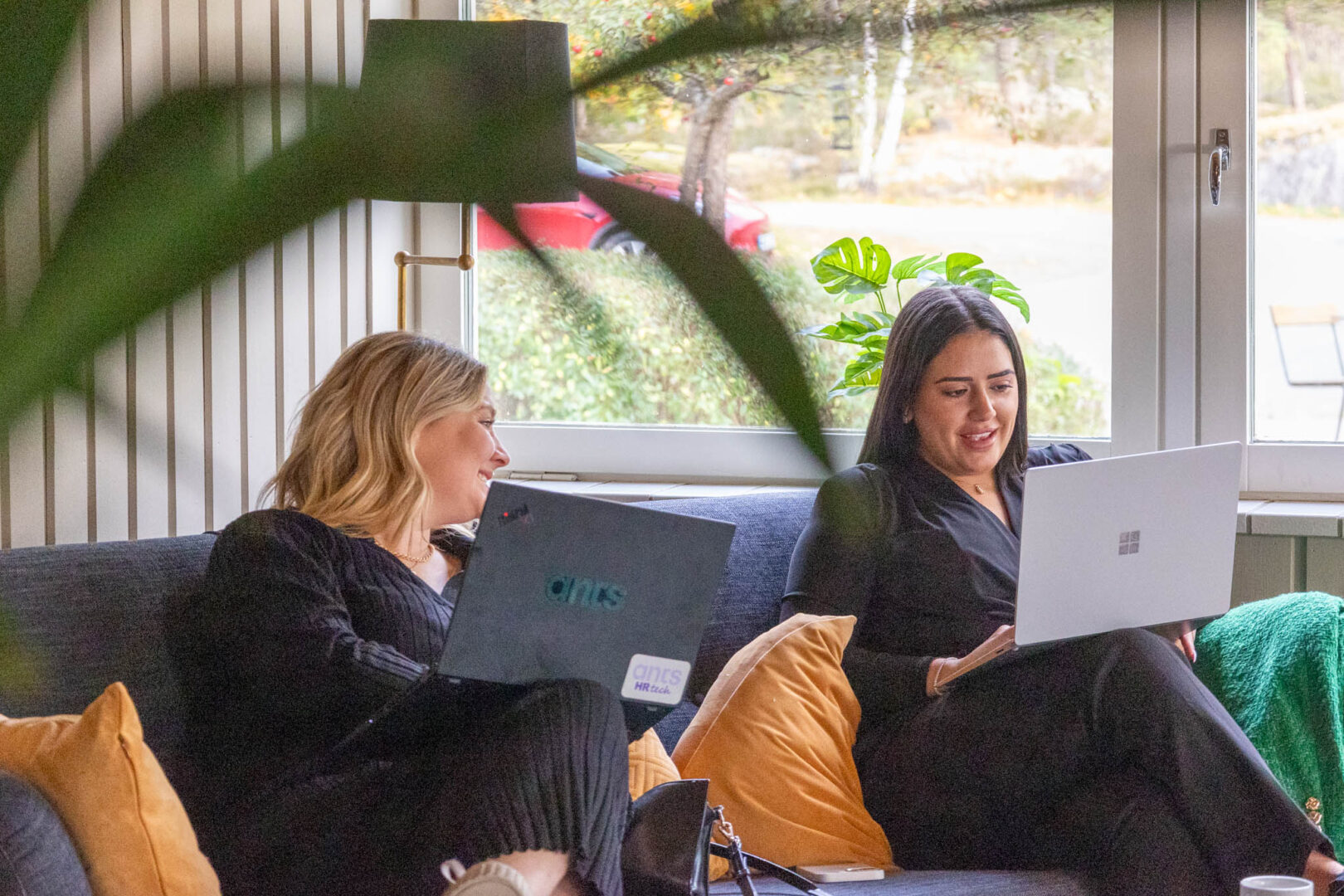 Två miljökonsulter sitter i en soffa med varsin laptop och diskuterar cirkulära lösningar för ett globalt energibolag.