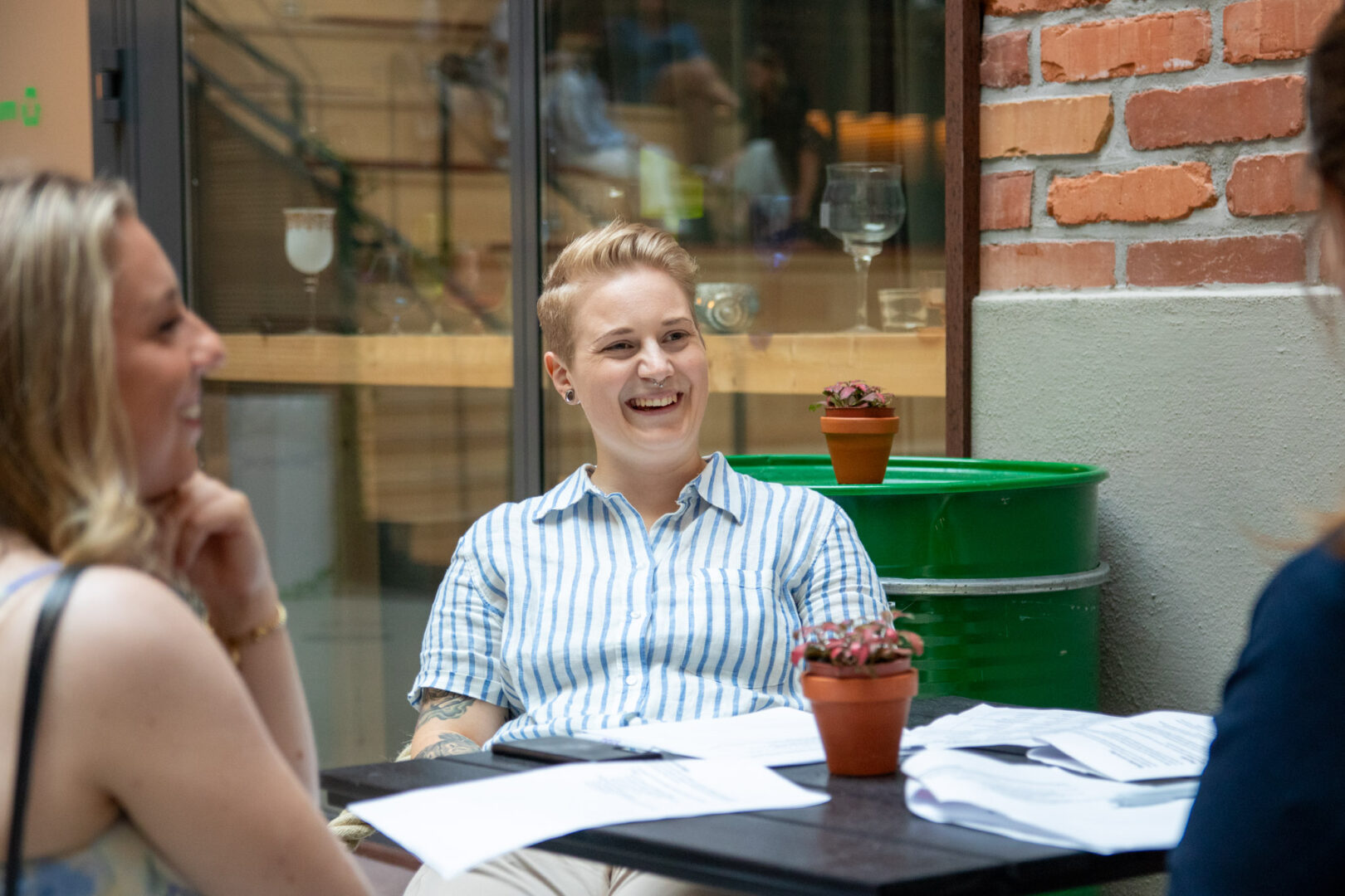 En Growth Marketing Manager på ett techföretag inom transport och logistik, som använder realtidsdata för att optimera CRM Marketing, sitter vid ett bord i ett industriellt kontorslandskap tillsammans med kollegor och diskuterar marknadsföringsstrategier.
