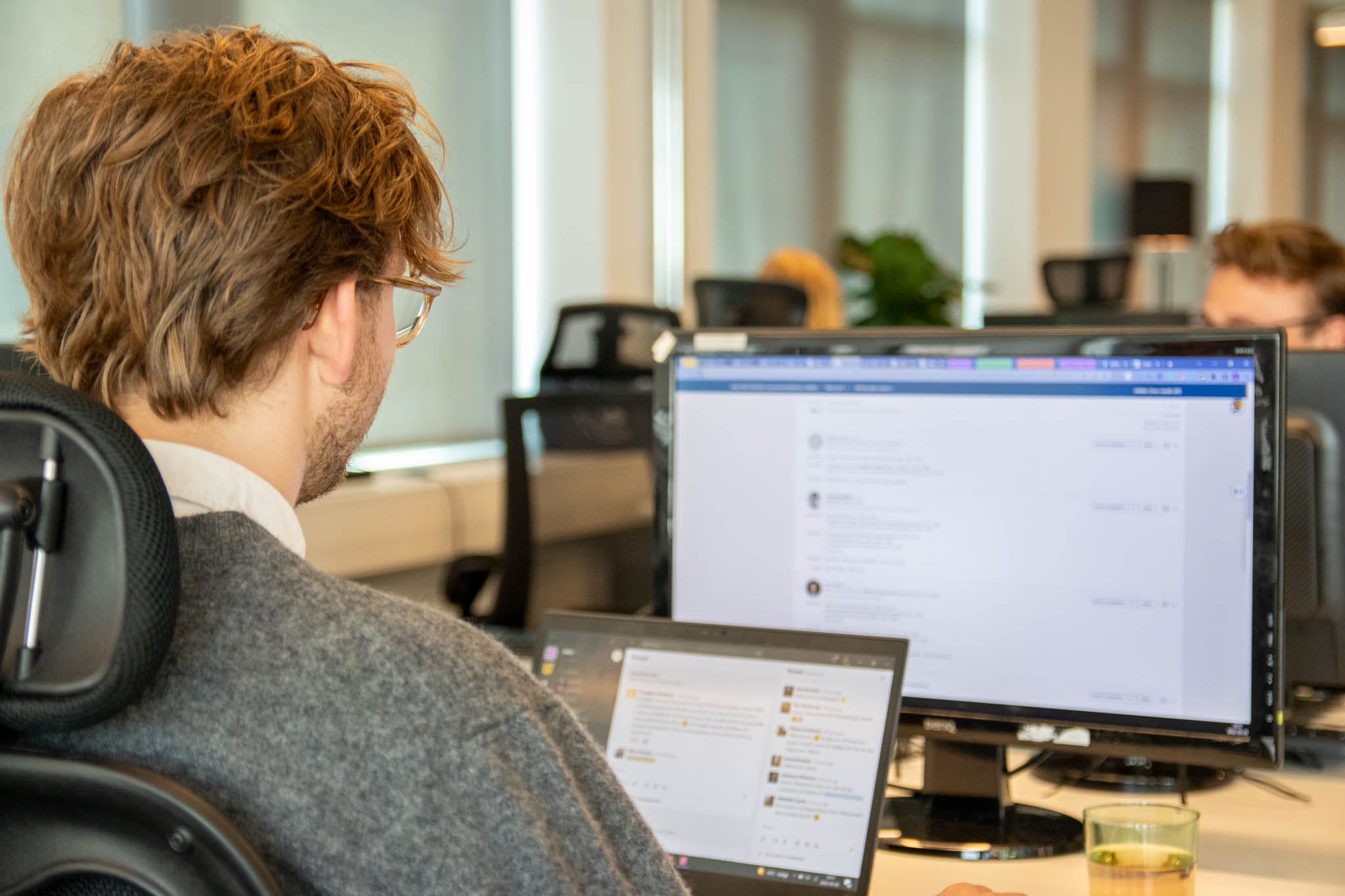 En dataanalytiker på en bank sitter framför sin laptop och kommunicerar digitalt med sitt team.