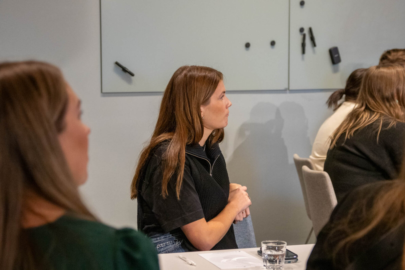 En CTO inom spelutveckling leder ett teammöte i ett ljust rum där medarbetarna, inkl. spelutvecklare och tekniska designers, lyssnar fokuserat på hur man kan optimera tekniska lösningar för att förbättra spelets prestanda och användarupplevelse.