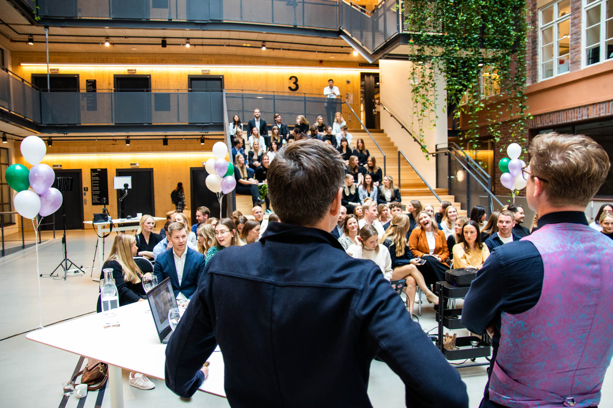 Grundarna av en tech-startup håller i en presentation på ett town hall meeting där de firar framgångar, delar företagets vision och inspirerar teamet att fortsätta växa och innovera på marknaden.